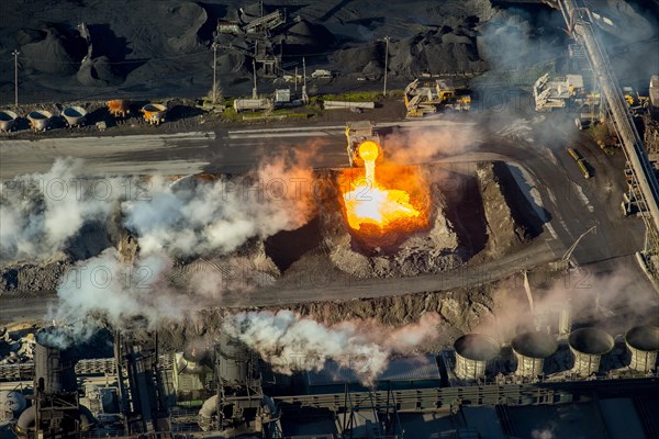 Glowing hot slag from iron production is tipped from a ladle car into a pit