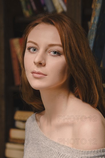 Young red-haired woman wearing a grey jumper