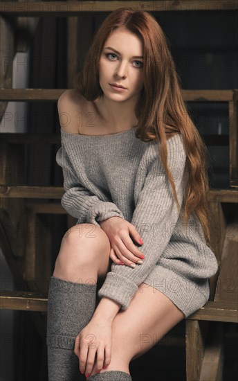 Young red-haired woman wearing a grey jumper