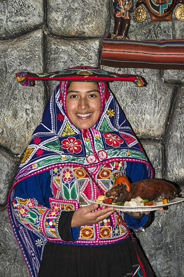 Woman serving roasted guinea pig Cuy chactado