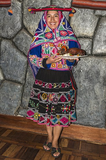 Woman serving roasted guinea pig Cuy chactado