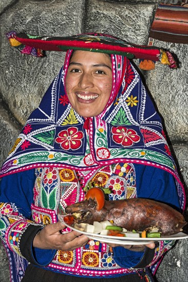 Woman serving roasted guinea pig Cuy chactado