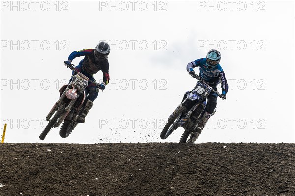 Two motorcyclists on motocross bikes riding on a dirt track