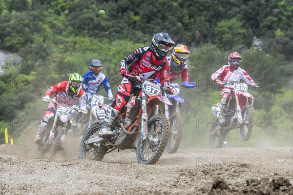 Group of motorcyclists on motocross bikes riding on a dirt track