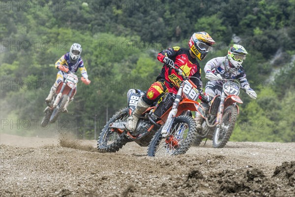 Group of motorcyclists on motocross bikes riding on a dirt track