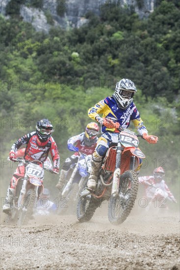 Group of motorcyclists on motocross bikes riding on a dirt track