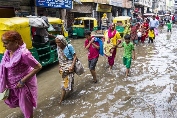 People and cycle rickshaws are moving through the flooded streets of the suburb Paharganj after a heavy monsoon rainfall