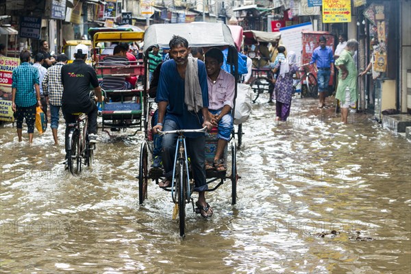 People and cycle rickshaws are moving through the flooded streets of the suburb Paharganj after a heavy monsoon rainfall
