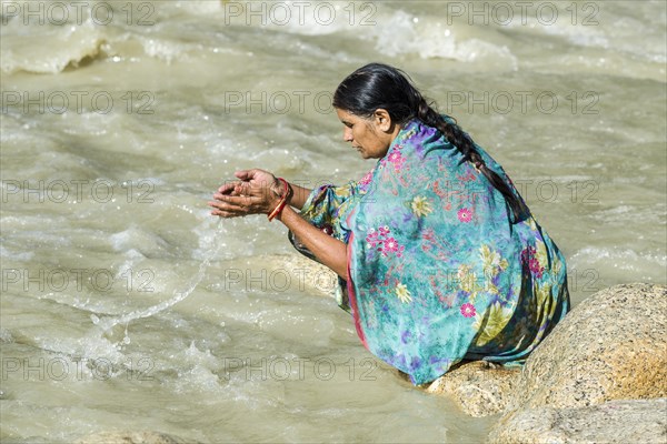 A female pilgrim at the banks of the river Ganges is praying