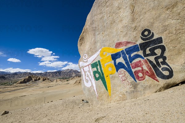 A big Tibetan Mani Stone with the Mantra "Om Mani Padme Hum" colorfully engraved on a hill above the Indus Valley