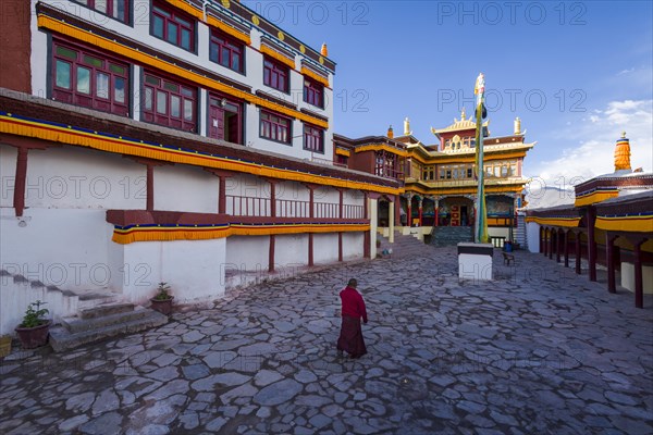 A monk is walking in the inner courtyard of Matho Gompa