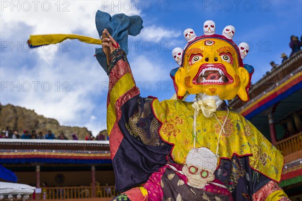 Monks with big wooden masks and colorful costumes are performing ritual dances at Hemis Festival in the courtyard of the monastery