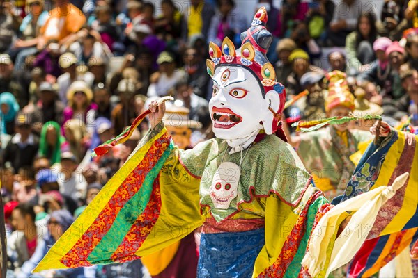 Monks with big wooden masks and colorful costumes are performing ritual dances at Hemis Festival in the courtyard of the monastery