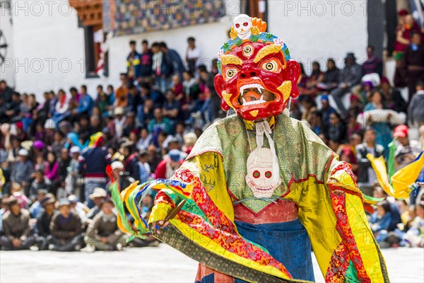 Monks with big wooden masks and colorful costumes are performing ritual dances at Hemis Festival in the courtyard of the monastery