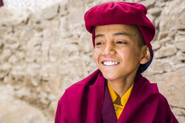 A portrait of a young monk of the Kagyu lineage of Buddhism in red clothes