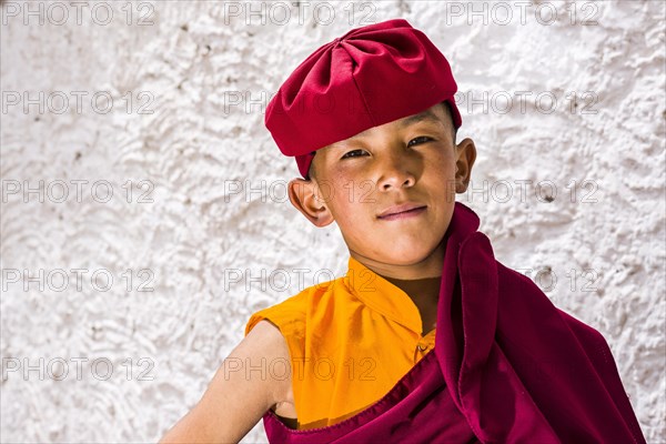 A portrait of a young monk of the Kagyu lineage of Buddhism in red clothes