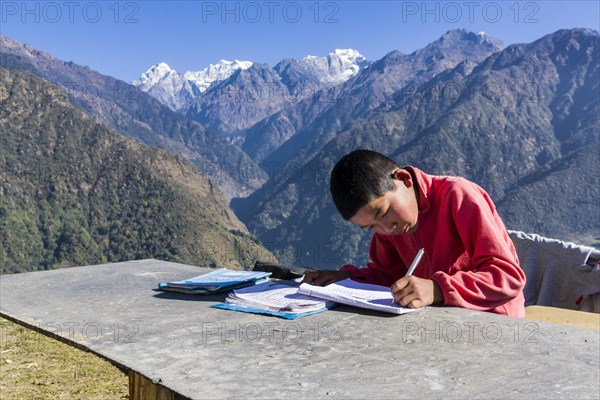 A schoolboy doing his homework outside