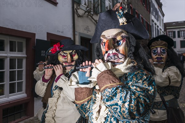 Many different groups of masked people walking through the streets of Basel