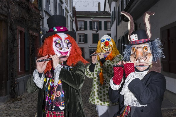 Many different groups of masked people walking through the streets of Basel