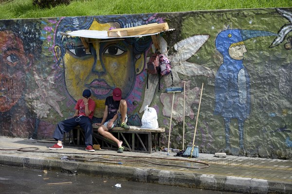 Young gang members sitting in front of graffiti wall