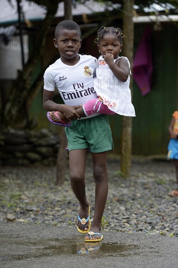 Boy carrying his little sister in his arms