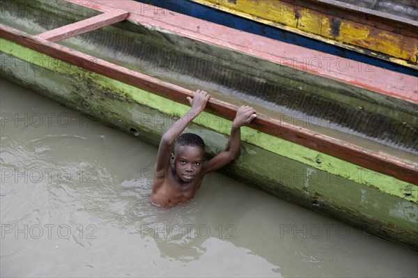 Boy playing beside boats in river