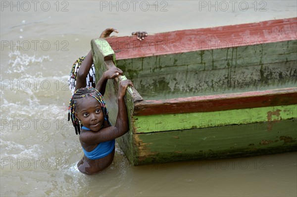 Girls playing beside boat in river