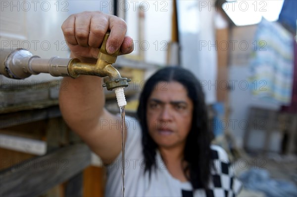 Woman opening faucet of the jointly used water tank