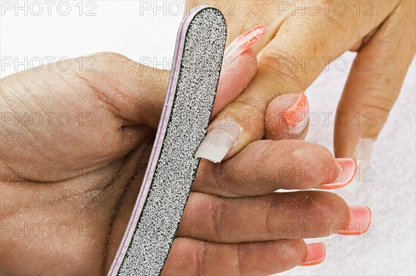 Beautician designing a customer's artificial fingernails