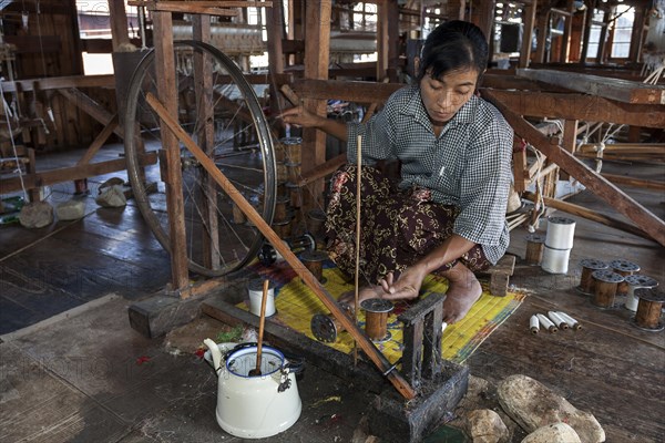 Local woman weaving threads from the stems of the lotus plant