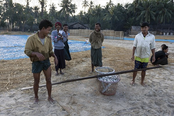 Native people standing around a basket full of fish