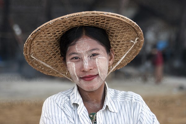 Local woman wearing a straw hat and Thanaka paste on her face