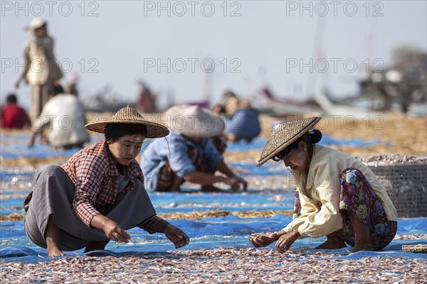 Local women wearing straw hats and Thanaka paste on their faces