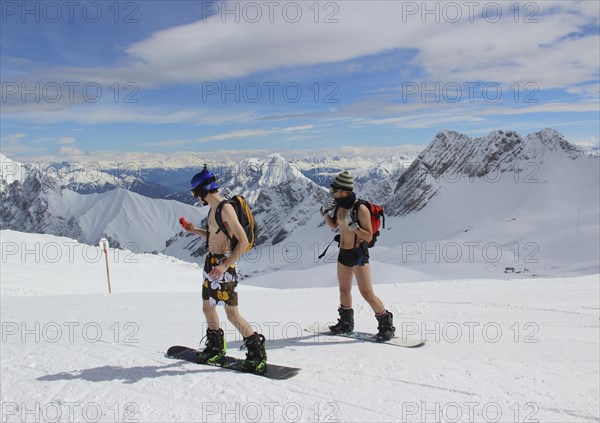 Two men are snowboarding in shorts and no shirt on the Zugspitzplatt