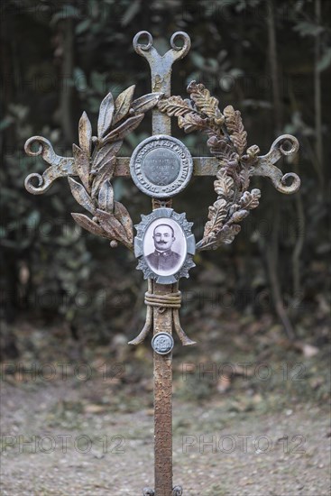 Iron cross on a grave with a sprig of laurel