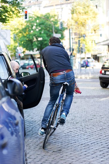 Cyclist in the city dodging a car door being opened