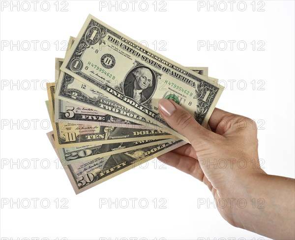 Woman's hand holding fan of various US Dollar notes