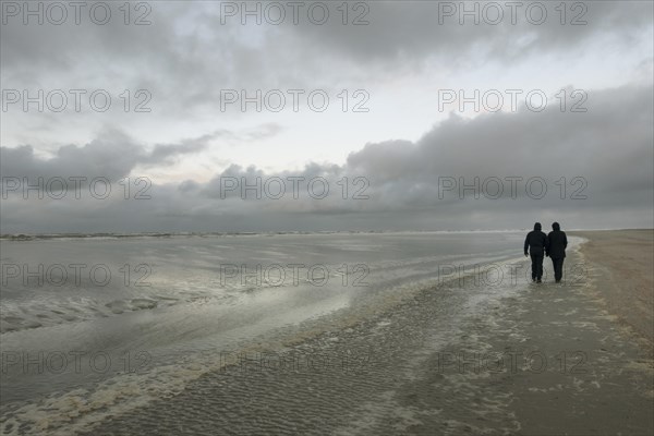 Walkers in bad weather on the beach of the North Sea island Langeoog