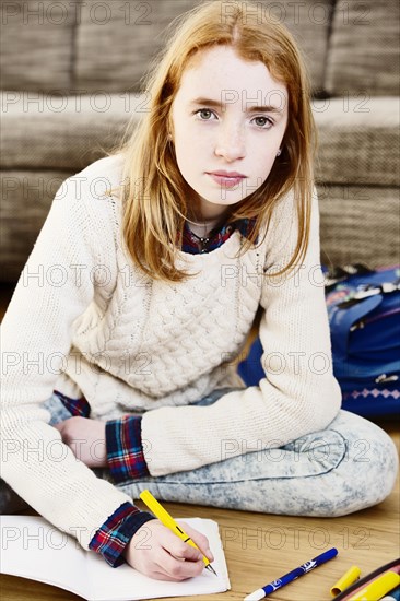 Girl doing her homework on the floor at home