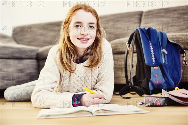 Girl doing her homework at home in the living room on the floor