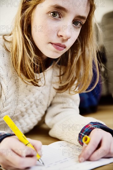 Girl doing her homework on the floor at home