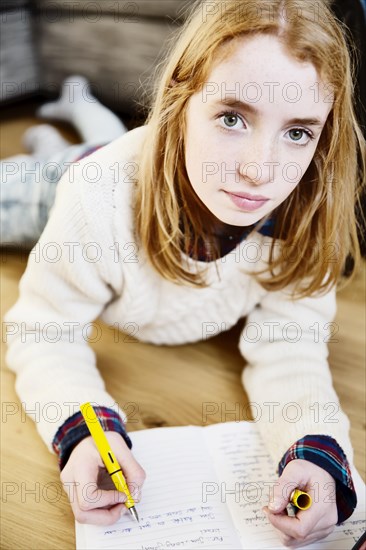 Girl doing her homework on the floor at home