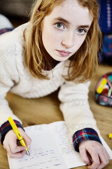 Girl doing her homework on the floor at home