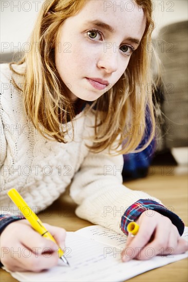 Girl doing her homework on the floor at home