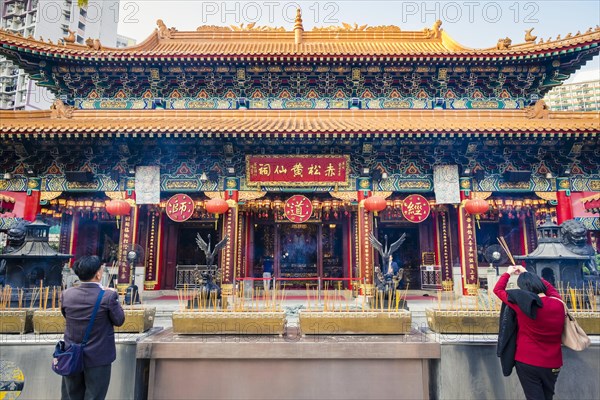 People praying in front of main altar house of Wong Tai Sin or Sik Sik Yuen Temple