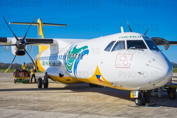 Workers unloading bags from a Cebu Pacific airplane on the apron at Francisco B. Reyes Airport