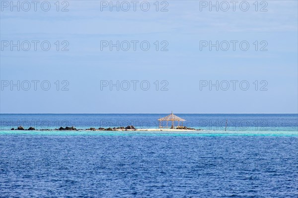 Bamboo structure on a small rocky beach in blue water at Banana Island