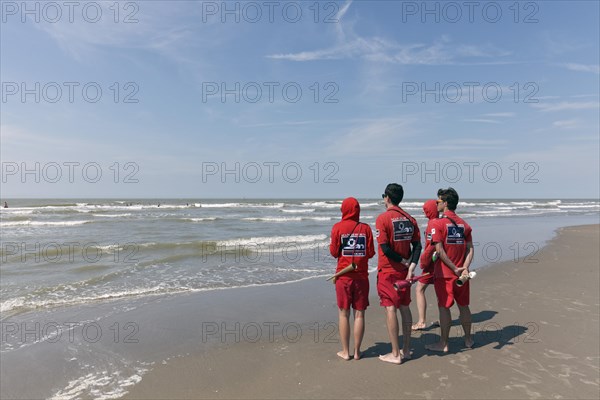 Four young lifeguards observing the sea from the beach