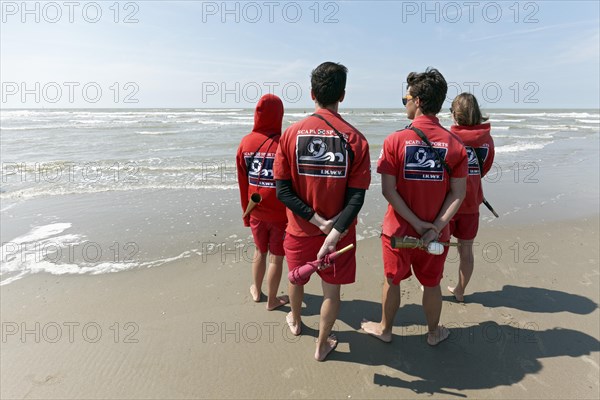 Four young lifeguards observing the sea from the beach