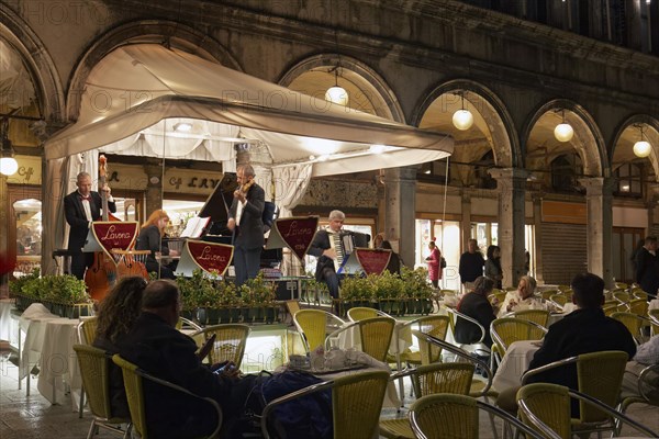 Musician on podium in front of Gran Caffe Laveno at night